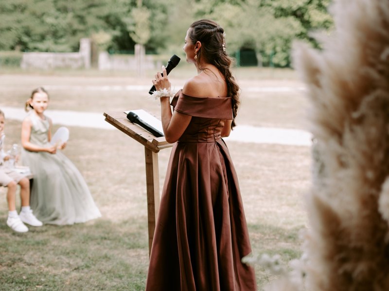 Bridesmaid prenant la parole au micro pendant la cérémonie laïque en extérieur