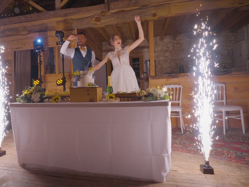Présentation du gâteau de mariage avec fontaines d'étincelles et mariés célébrant