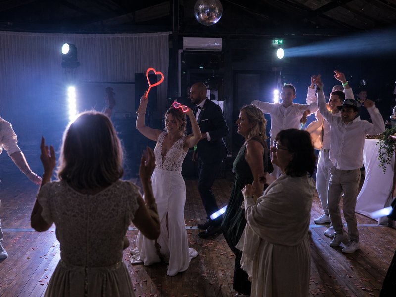 Invités bras levés avec cierges magiques en forme de cœur sur la piste de danse